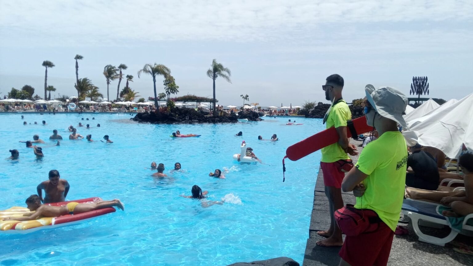 Imagen que combina el mantenimiento de la piscina con la supervisión de un socorrista.